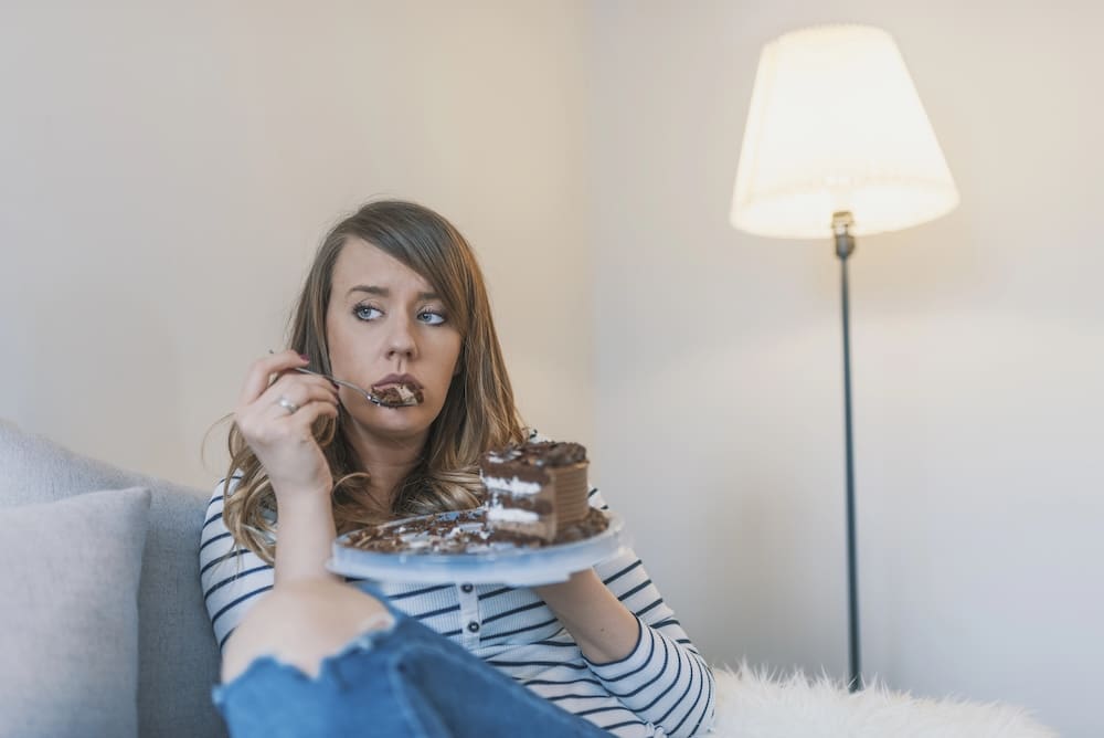woman eating cake on the couch