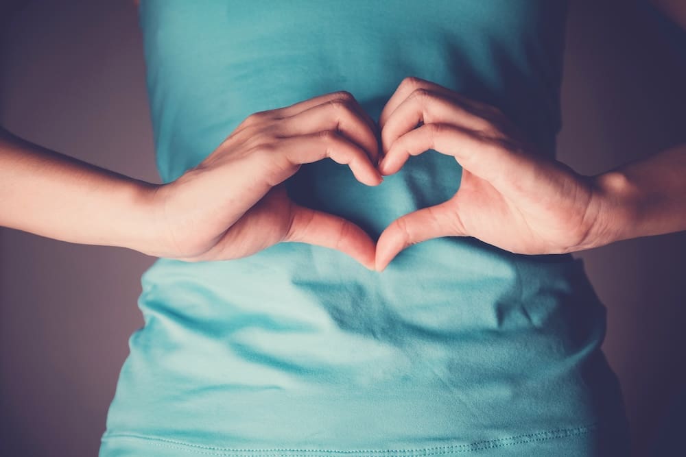 Woman hands making a heart shape on her stomach, healthy bowel digestion, probiotics for gut health